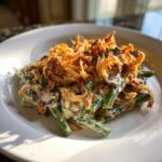 A close-up serving of creamy green bean casserole topped generously with crispy fried onions.