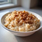 A close-up of creamy rice pudding generously sprinkled with cinnamon in a white bowl.