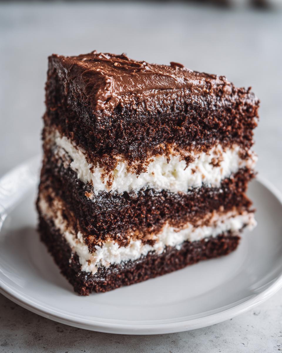 Close-up of a rich slice of german chocolate cake recipe with dark layers and white coconut-pecan filling.