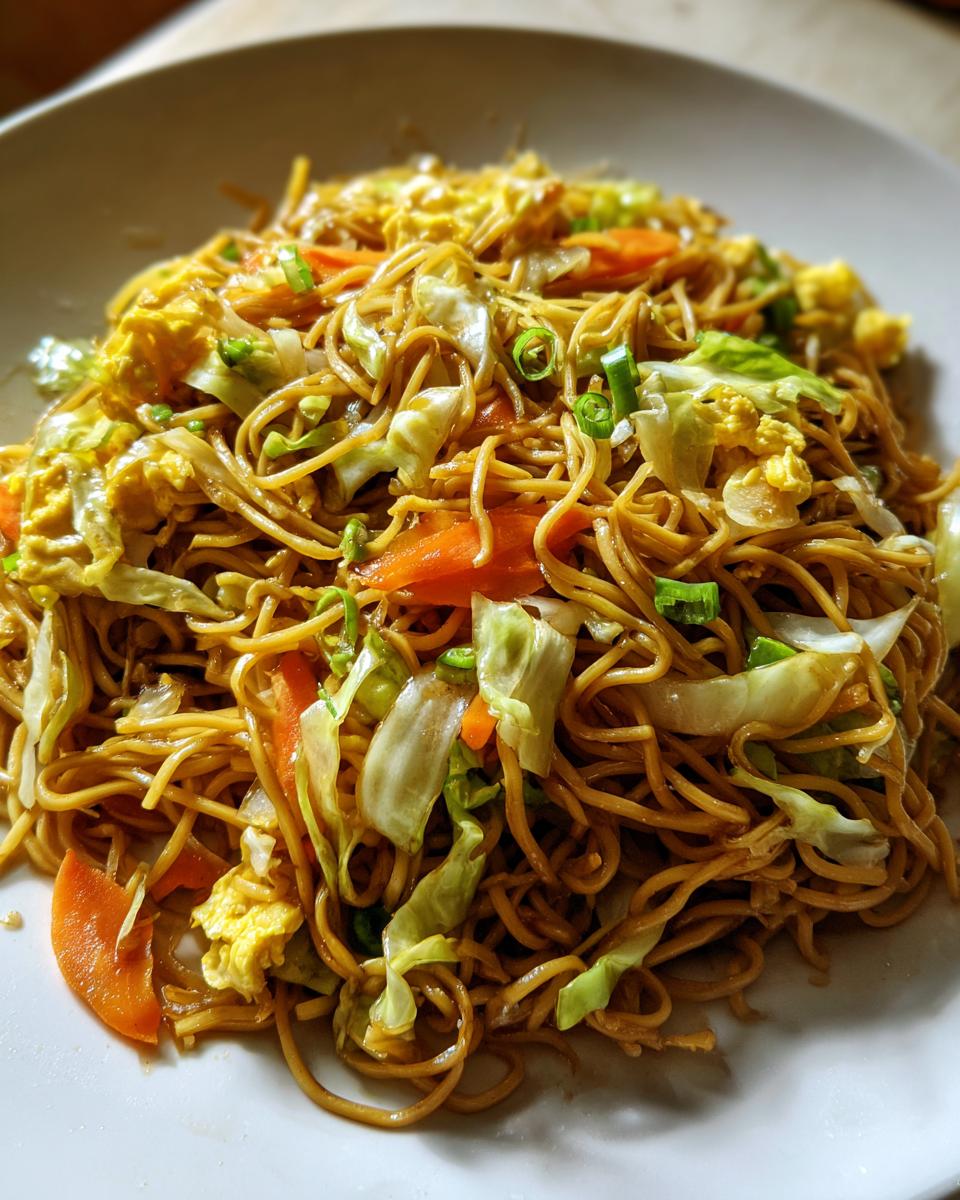 A close-up of a generous serving of delicious fried noodles mixed with scrambled egg, carrots, and cabbage.