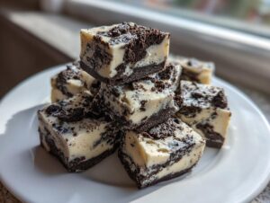 A stack of rich, creamy Oreo fudge squares with dark cookie pieces visible throughout the white base.
