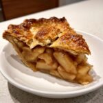 Close-up of a perfect slice of apple pie showing thick, gooey apple filling and a golden, flaky crust.
