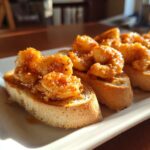 Close-up of baked shrimp toast slices topped with glistening, seasoned shrimp.