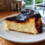 A creamy slice of Basque burnt cheesecake showing its signature dark, caramelized top and light interior.