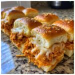 Close-up of freshly baked buffalo chicken sliders filled with shredded spicy chicken and melted white cheese.