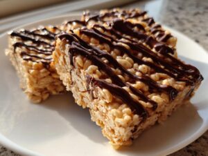 Close-up of chewy peanut butter rice krispie treats drizzled generously with dark chocolate.