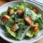 Close-up of a fresh caesar salad featuring crisp romaine lettuce, creamy dressing, grated parmesan, and golden croutons.