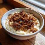 A bowl of creamy caramelized onion dip generously topped with dark, rich caramelized onions.