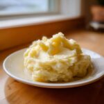A generous serving of creamy, fluffy Boursin mashed potatoes piled high on a small white plate.