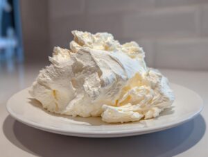 A generous, fluffy mound of freshly made vanilla buttercream frosting sitting on a white plate.