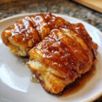 Close-up of a warm, gooey apple dumpling covered in a shiny caramel glaze.
