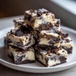 A tempting stack of white and dark chocolate Oreo fudge squares topped with cookie crumbs.