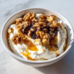 Close-up of a bowl of creamy whipped ricotta dip drizzled with honey and topped with walnuts and dried fruit.