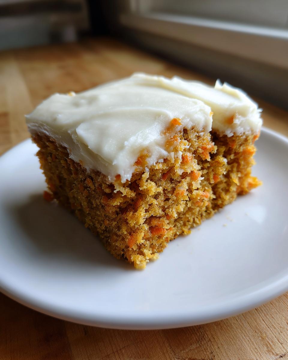 A close-up of a moist square slice of amazing carrot cake bars topped with thick cream cheese frosting.