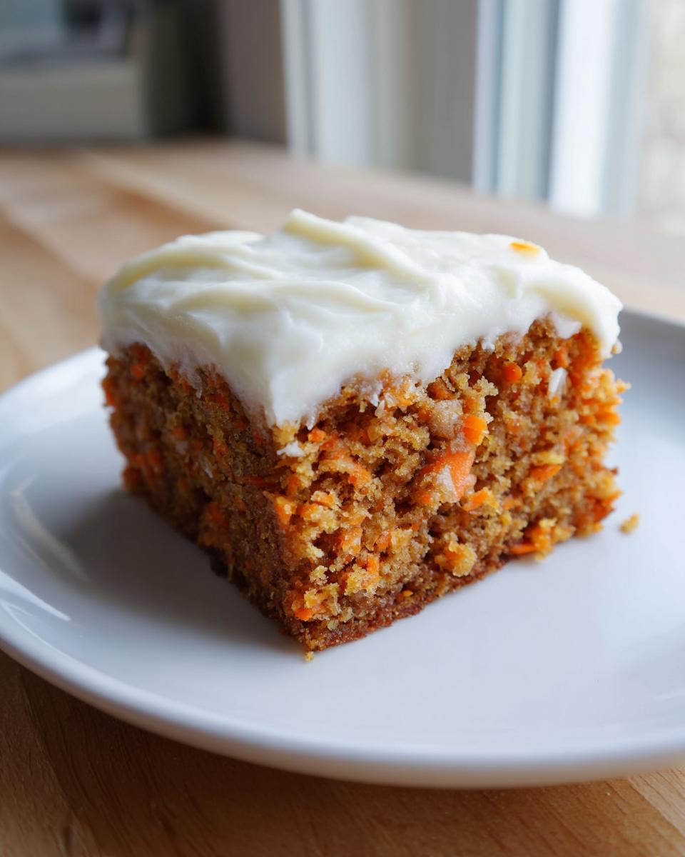 A close-up of a square slice of amazing carrot cake bars topped with thick cream cheese frosting on a white plate.