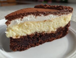 A close-up slice of amazing italian love cake showing a dark chocolate base, creamy yellow layer, white topping, and chocolate dusting.