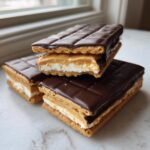 Three homemade Buckeye graham crackers stacked, showing peanut butter, marshmallow, and chocolate coating.