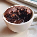 Close-up of a warm Cottage Cheese Microwave Brownie in a white mug with a molten chocolate center.