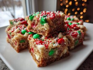 Close-up of stacked Christmas cookie bars topped with red, green, and white sprinkles and chocolate chips.