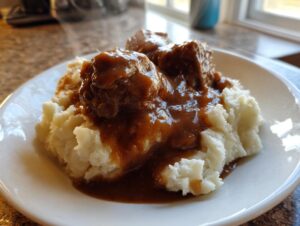 Close-up of meatballs smothered in rich homemade brown gravy served over fluffy mashed potatoes.
