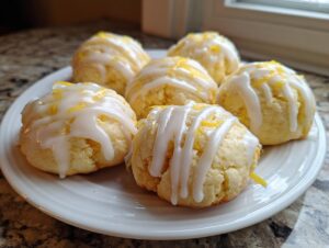 A plate of soft Italian ricotta cookies drizzled with white glaze and lemon zest.