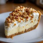 A perfect slice of rich million dollar pie featuring a graham cracker crust, creamy filling, and chopped nut topping.