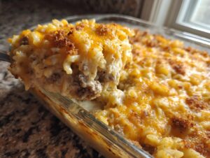 A spoonful of creamy sour cream beef noodle casserole topped with melted cheddar cheese and breadcrumbs.