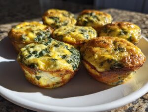 A plate of freshly baked, golden brown spinach egg bites, perfect for a quick breakfast.