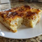A close-up of a thick, creamy slice of ultimate scalloped potatoes with a golden-brown, cheesy top.