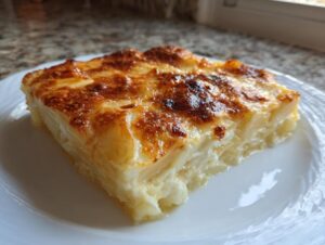 A thick, square slice of creamy scalloped potatoes with a golden-brown, cheesy crust.